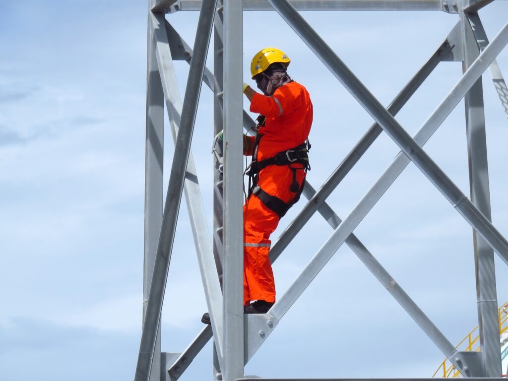 Rope access worker in red uniform on metal structure
